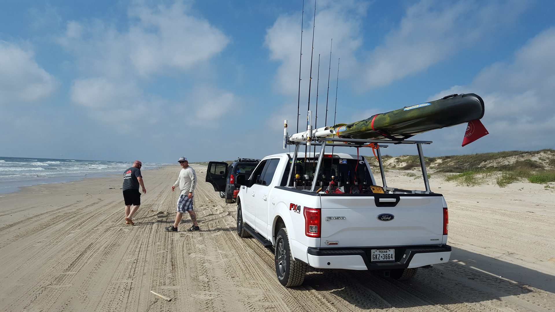Pickup truck with kayak and fishing rods on the beach