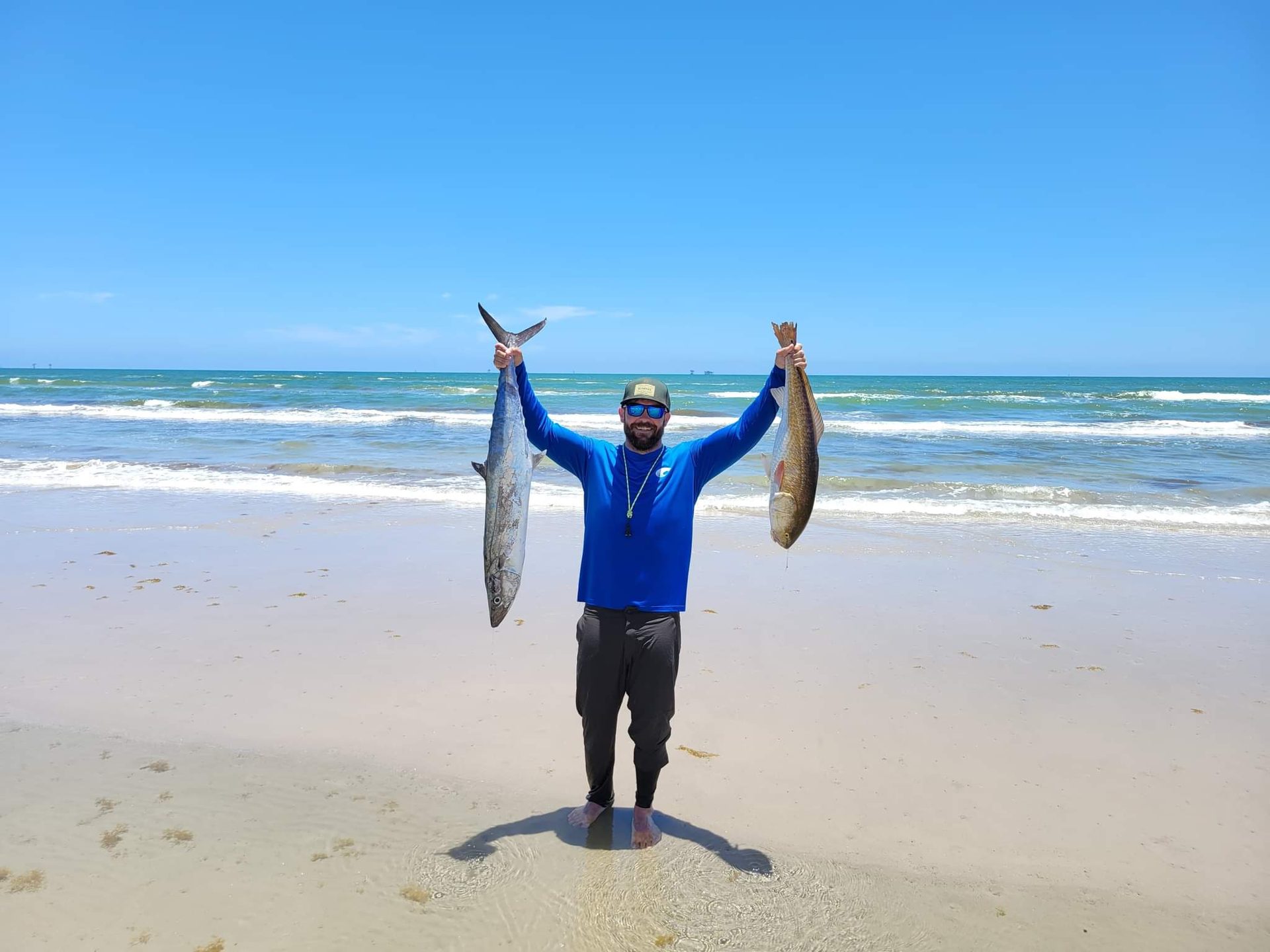 Angler holding redfish and mackerel on the beach